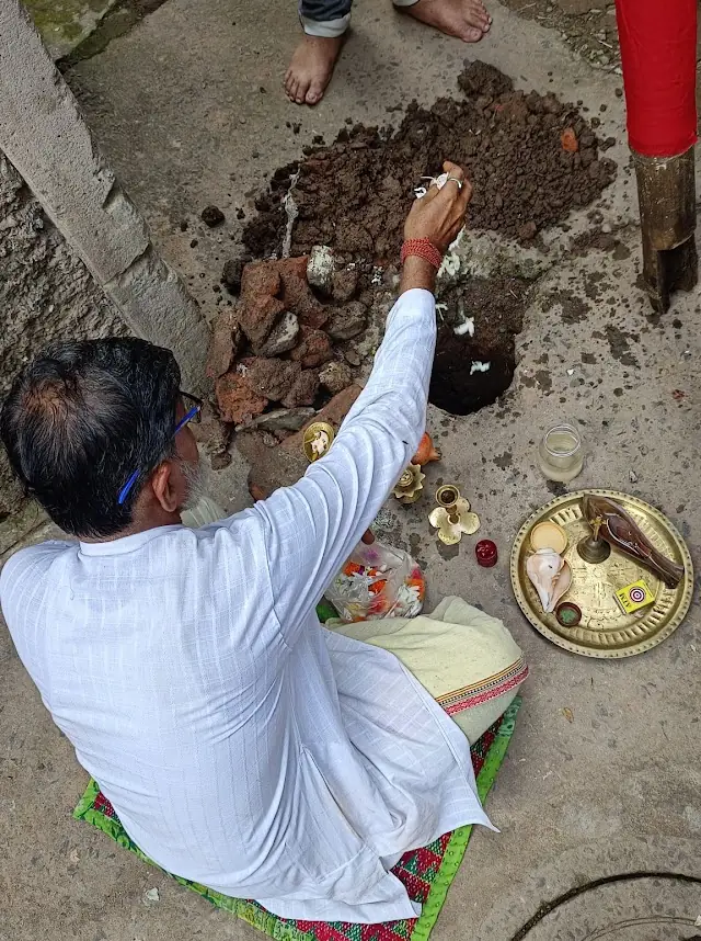 The priest offers prayers at the base of the khuti