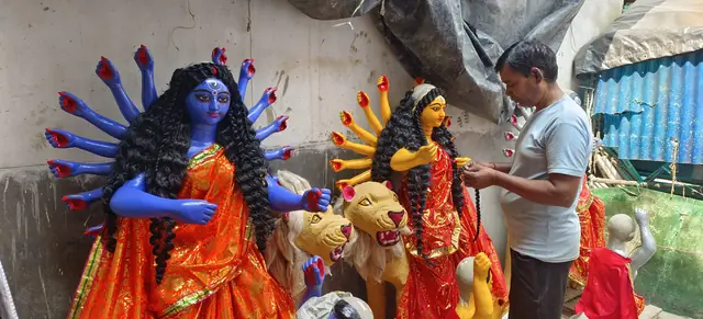 An artisan dresses the goddesses in red and gold